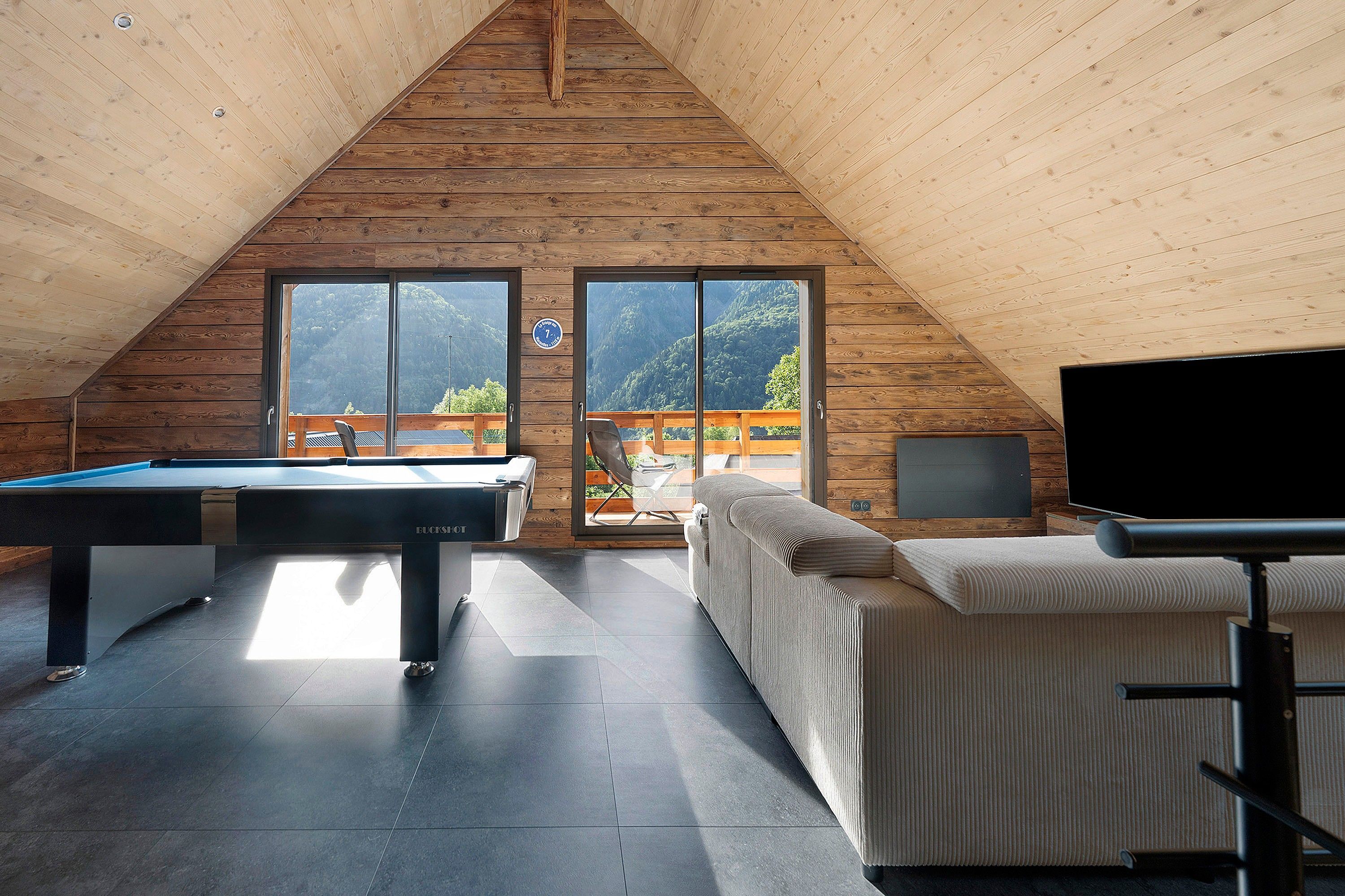 A modern interior with a pool table, a sofa, and a TV.