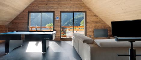Un interior moderno con mesa de billar, sofá y televisor.