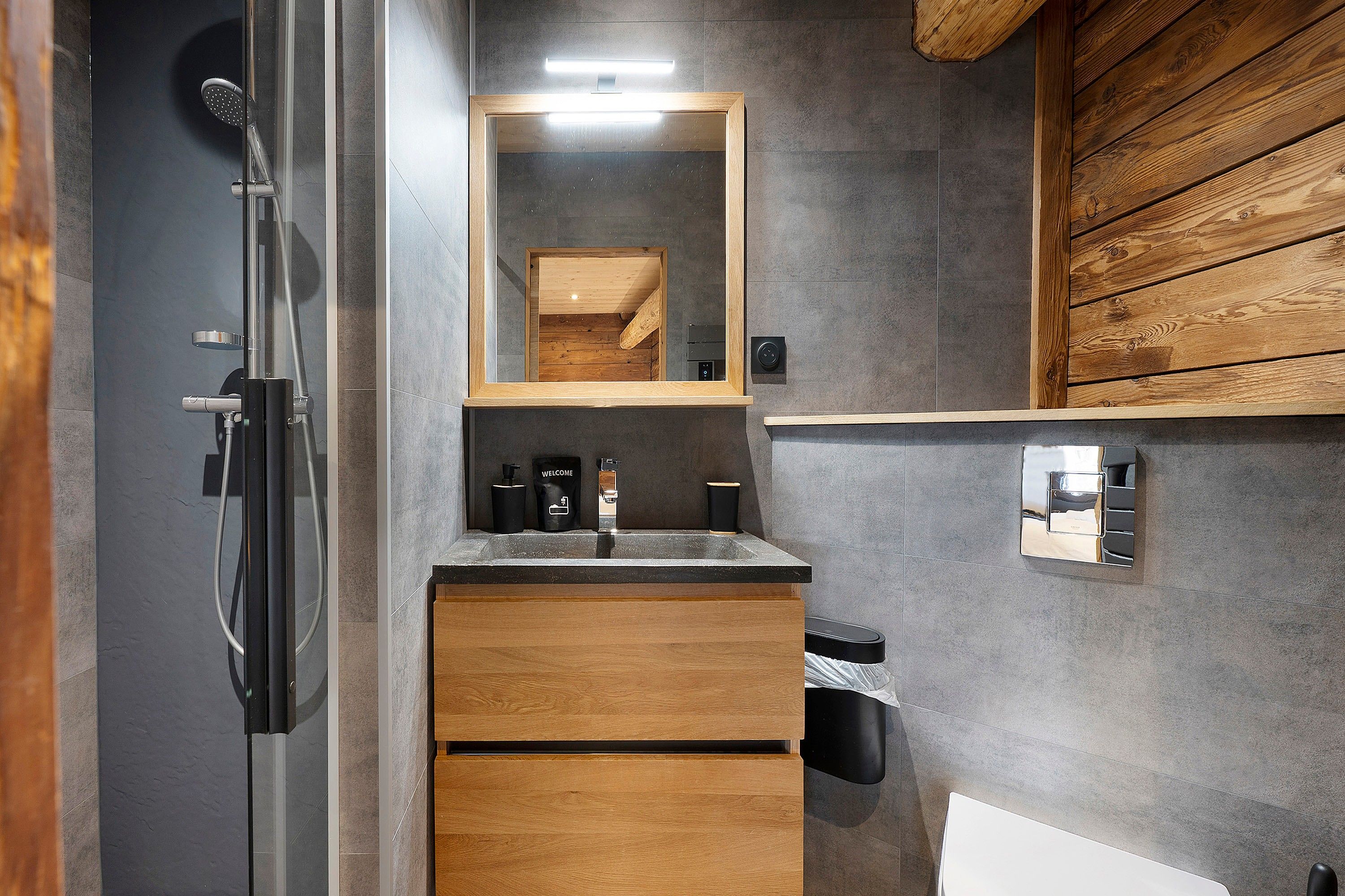 A modern bathroom with a shower, a sink with a mirror, and a wooden vanity.
