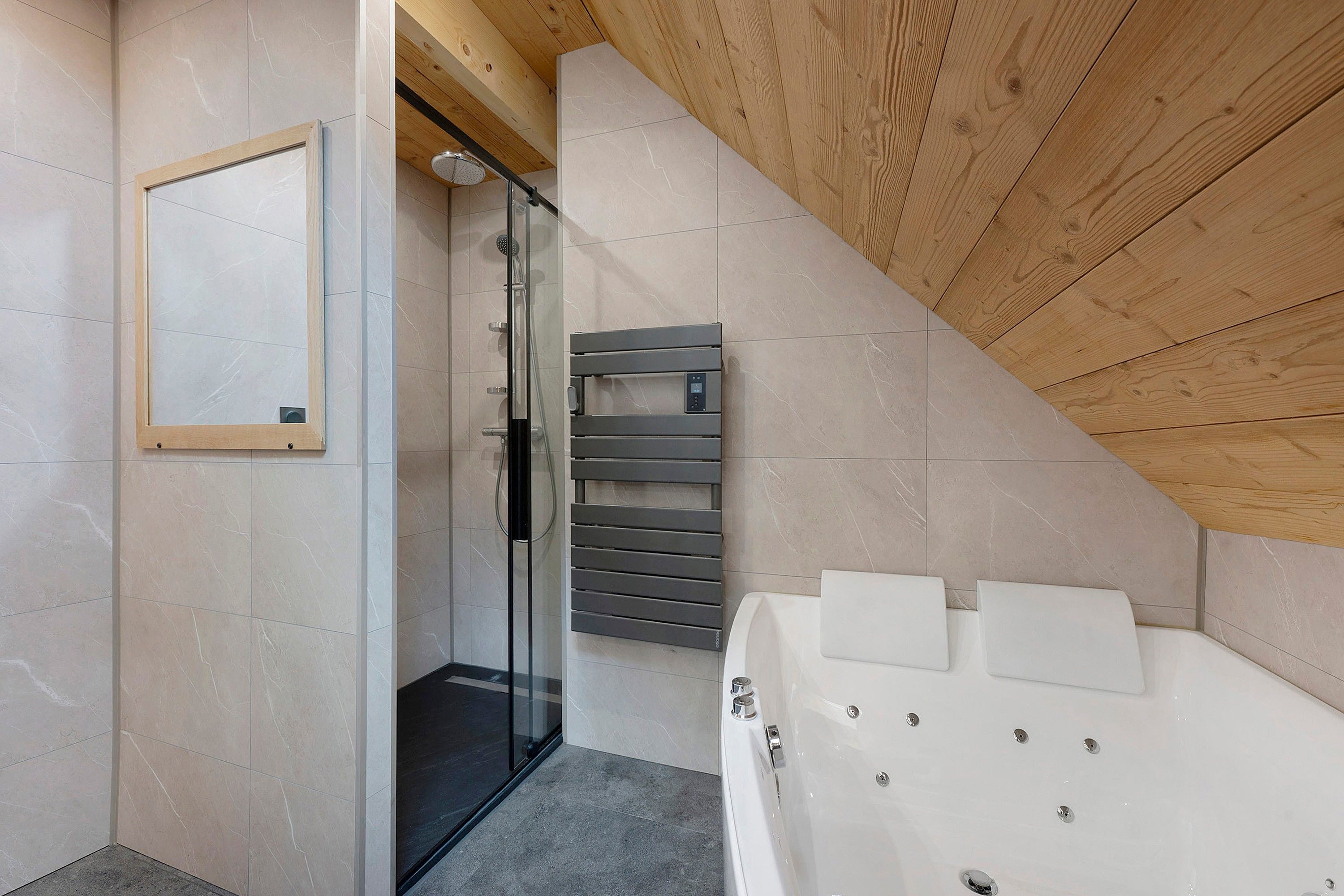 A modern bathroom with a glass shower enclosure, a built-in towel rack, and a white bathtub.