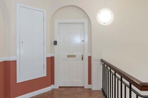 A hallway with a white door, a mailbox, and a light fixture on the wall. - GuestReady - Spacious 1bed in Newington, Edinburgh (Edinburgh)