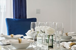 Une table dressée avec de la vaisselle blanche, comprenant des bols et des assiettes, et une rangée de verres transparents.