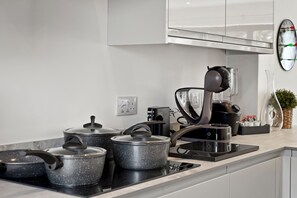 Eine moderne Küche mit eingebautem Herd, Töpfen, einer Kaffeemaschine und einer Uhr an der Wand.