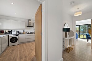 Eine moderne Küche mit Einbauwaschmaschine, Holzschränken und Blick auf den Außenbereich.