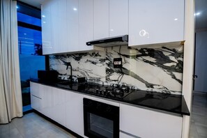 A modern kitchen with white cabinetry, a black countertop, and a marble backsplash. - Work friendly, Family Friendly apartments. Peaceful and Serene. (Lusaka Province)