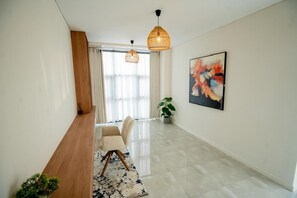 A modern interior with a wooden bench, a dining area, a potted plant, and a large abstract painting on the wall. - Work friendly, Family Friendly apartments. Peaceful and Serene. (Lusaka Province)