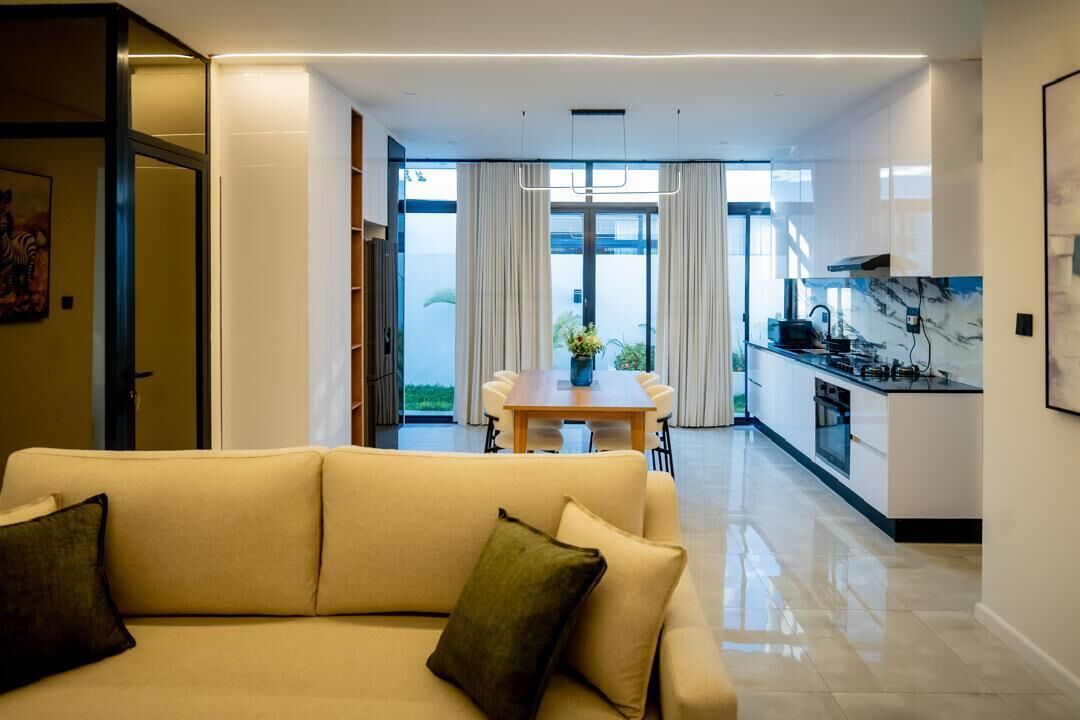 A modern living room with a sofa and a dining area in the background.