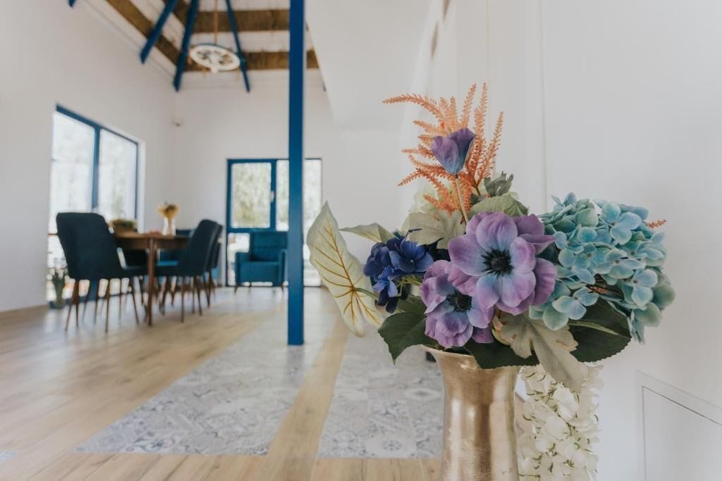 Um interior moderno com área de jantar, uma janela grande e um vaso decorativo com flores.