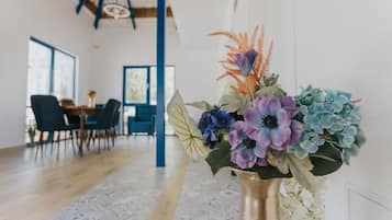 Um interior moderno com área de jantar, uma janela grande e um vaso decorativo com flores.