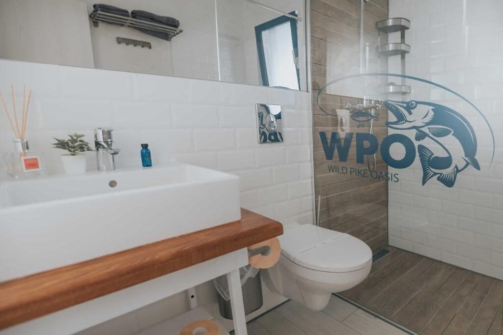 A modern bathroom with a white sink, wooden countertop, and a toilet.