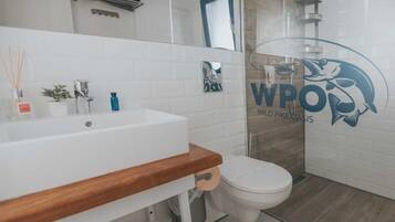 A modern bathroom with a white sink, wooden countertop, and a toilet.