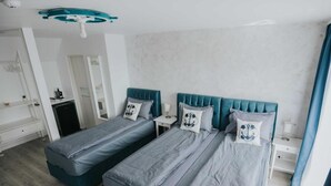 A bedroom with two beds, a desk, and a chair.