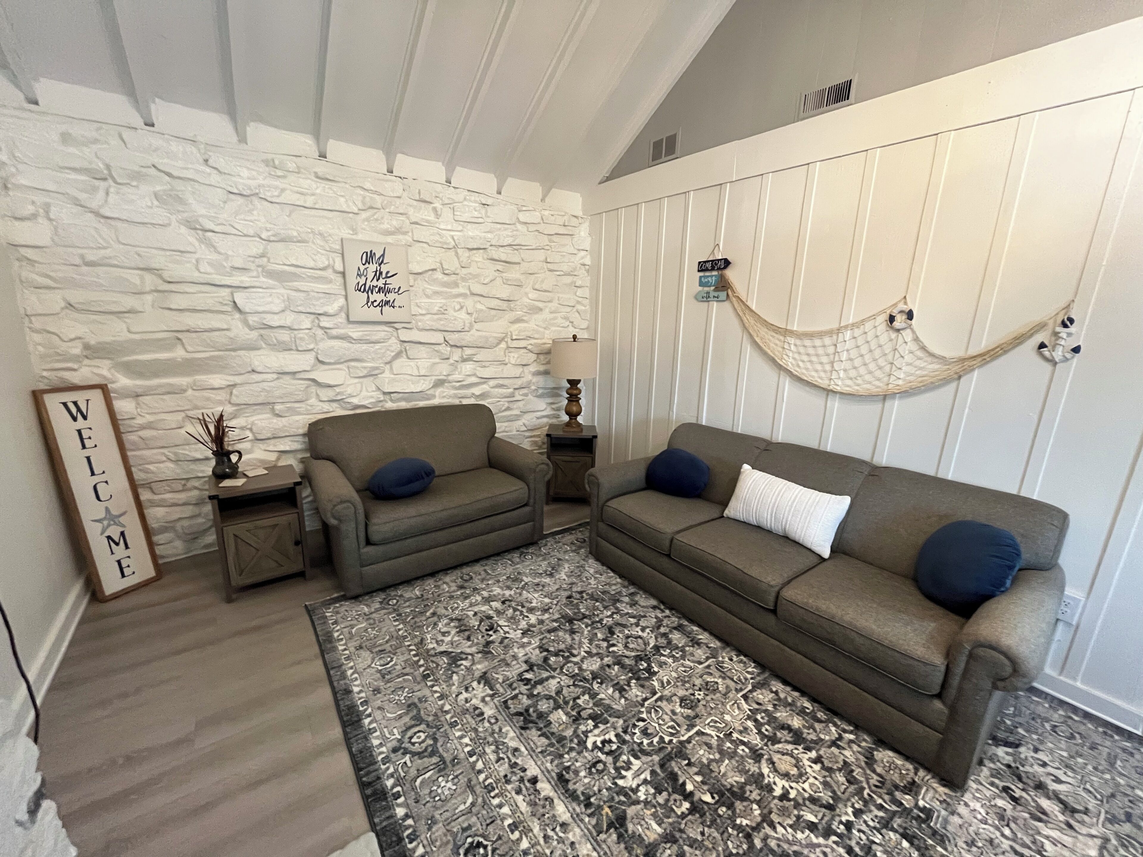 A living room with a stone wall, two sofas, a patterned rug, and a hammock.