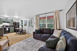 Ein modernes Wohnzimmer mit einer Couch, einem Esstisch und einer Küche im Hintergrund.