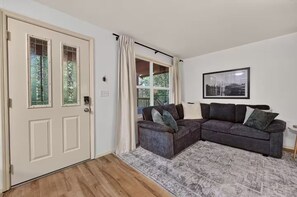 A living room with a dark grey sectional sofa, a patterned rug, and a framed picture on the wall.
