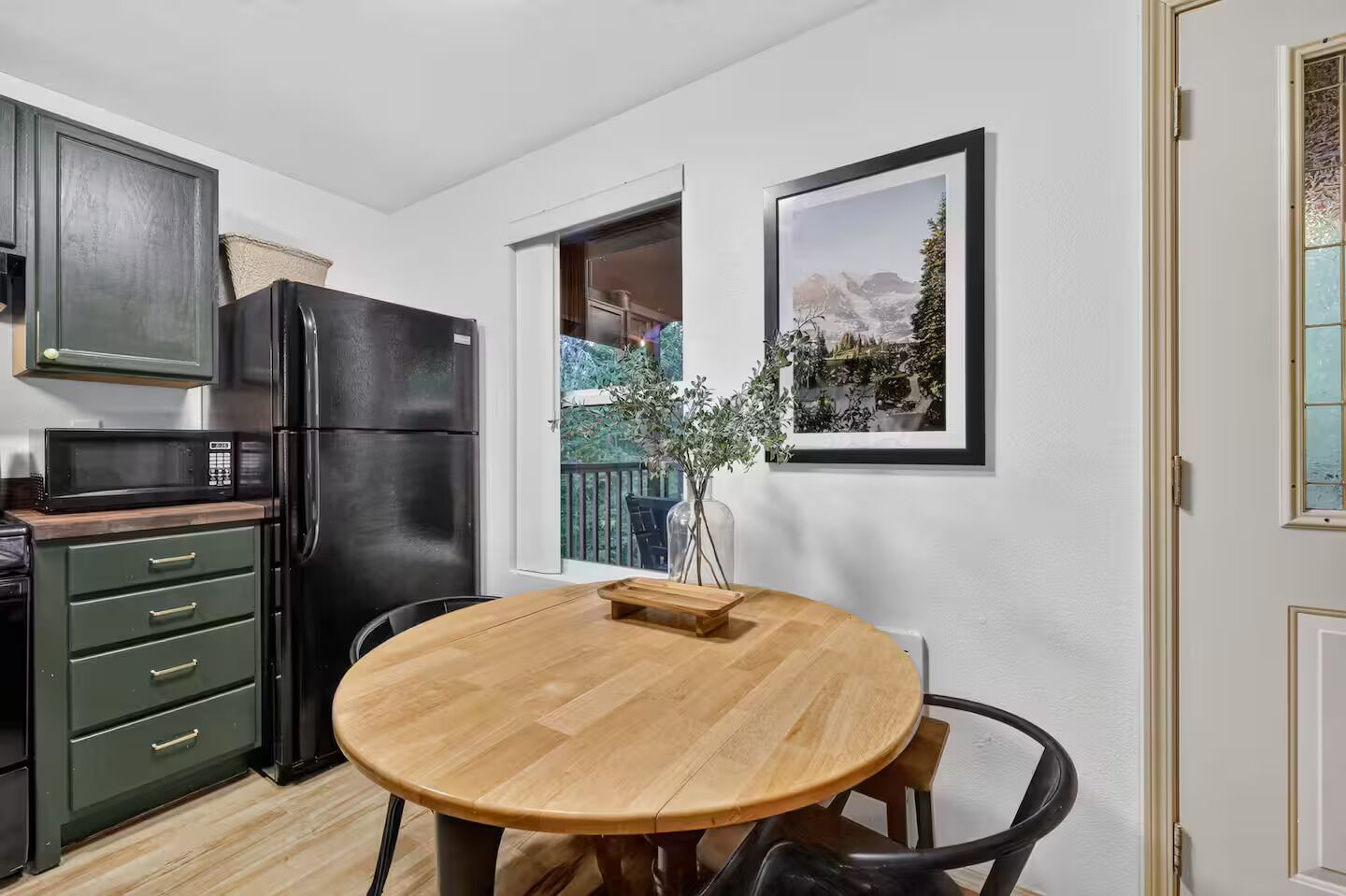 Una cocina compacta con una mesa de comedor de madera, un refrigerador y un microondas.