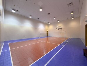 Eine Sporthalle mit Basketballfeld, Volleyballnetz und Basketballkorb.