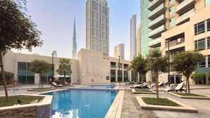 Ein Swimmingpool mit Liegestühlen und Blick auf ein hohes Gebäude im Hintergrund.