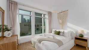 Ein modernes Schlafzimmer mit einem großen Bett, einem Nachttisch, einer Wanddekoration aus Makramee und einem Fenster mit Vorhängen.
