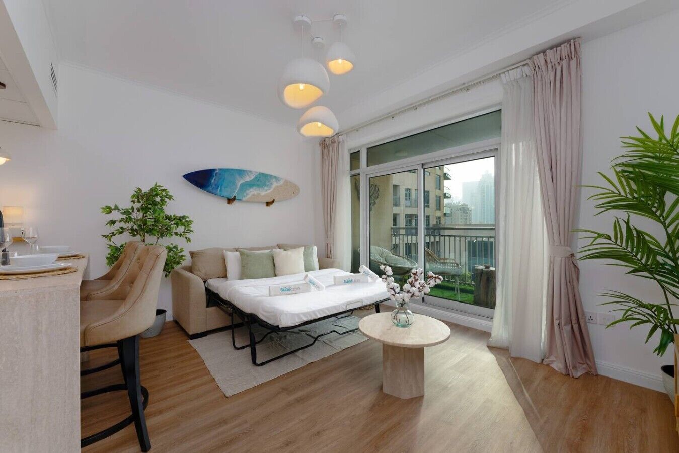 Ein modernes Hotelzimmer mit Bett, Essecke, Sofa, rundem Tisch und einem großen Fenster mit Vorhängen.