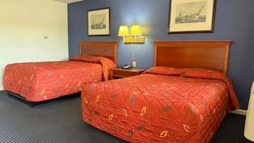 Et hotelværelse med to senge, et natbord med en lampe og to billeder i rammer på væggen.