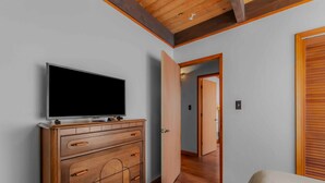 A room with a wooden dresser, a television on top, and a door leading to another room. - Lakewood Escape 3BR Retreat (South Lake Tahoe)