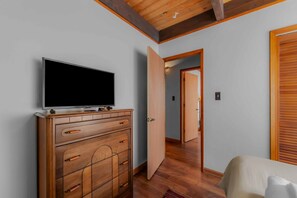 Ein Zimmer mit einem Holzkoffer, einem Fernseher darauf und einer Tür zu einem anderen Raum.