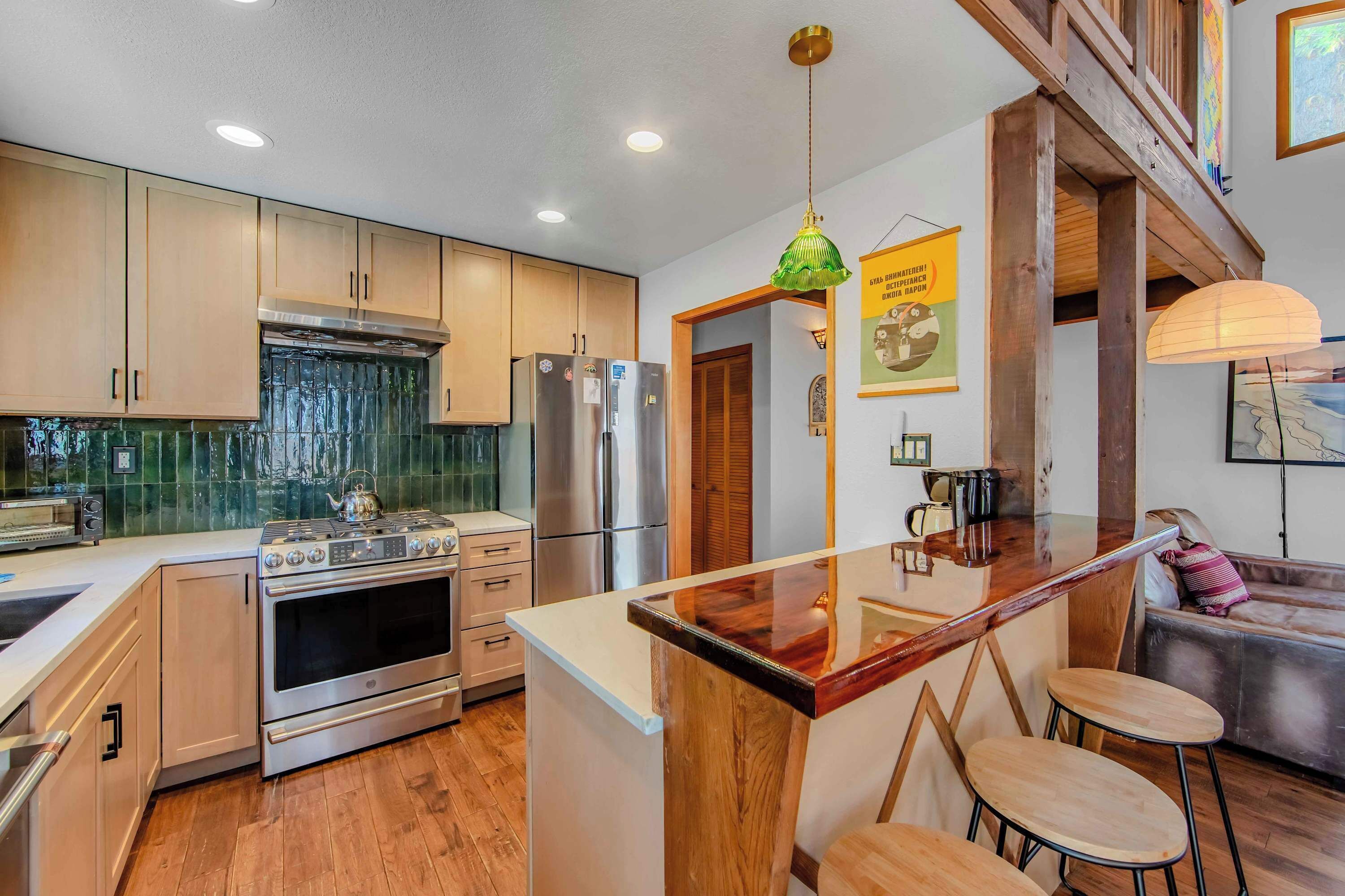 A modern kitchen with stainless steel appliances, wooden cabinets, and a central island with bar stools.