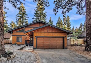 A modern two-story house with a large garage, surrounded by tall pine trees. - Lakewood Escape 3BR Retreat (South Lake Tahoe)