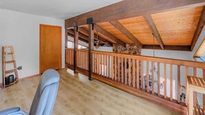 A room with a wooden ceiling, a stone wall, a wooden railing, and a door. - Lakewood Escape 3BR Retreat (South Lake Tahoe)