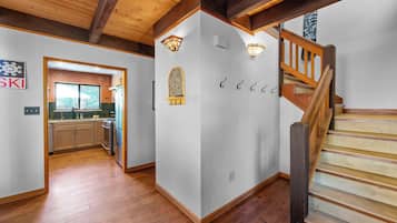 A modern interior with a wooden staircase, a kitchen with a large window, and a wall-mounted light fixture.