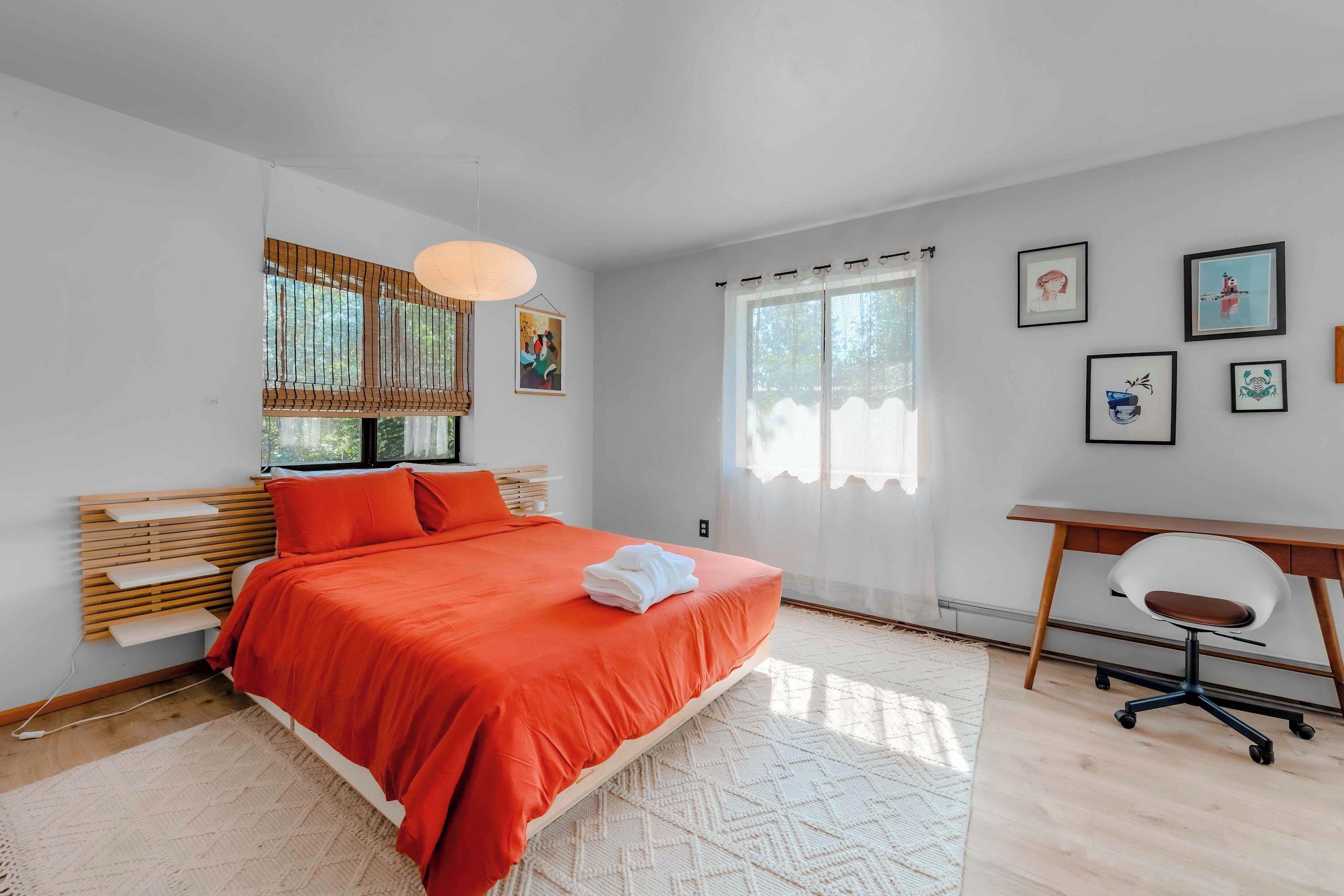 A modern bedroom with a bed, a desk, and a chair.