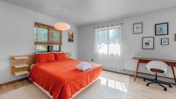 A modern bedroom with a bed, a desk, and a chair.