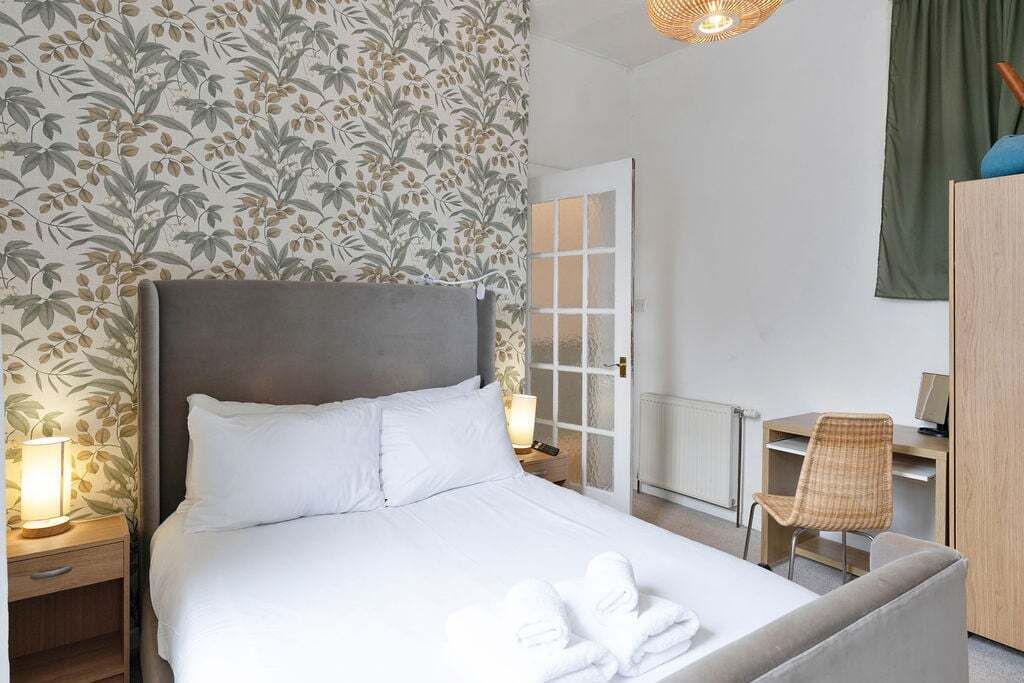 A hotel room with a bed, a desk, a chair, and a door.