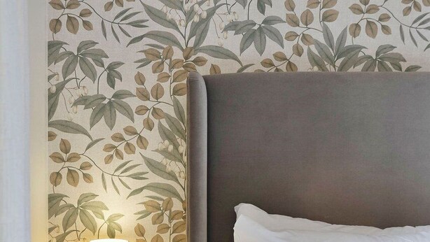 A bedroom with a bed, a bedside table with a lamp, and a wall with a leafy pattern. - GuestReady - Charming 1Bed near Edinburgh Beach (Edinburgh)