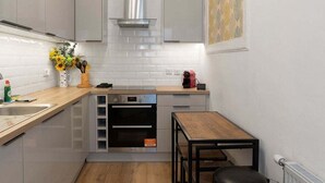 A compact kitchen with white cabinets, a built-in oven, and a small dining table. - GuestReady - Charming 1Bed near Edinburgh Beach (Edinburgh)
