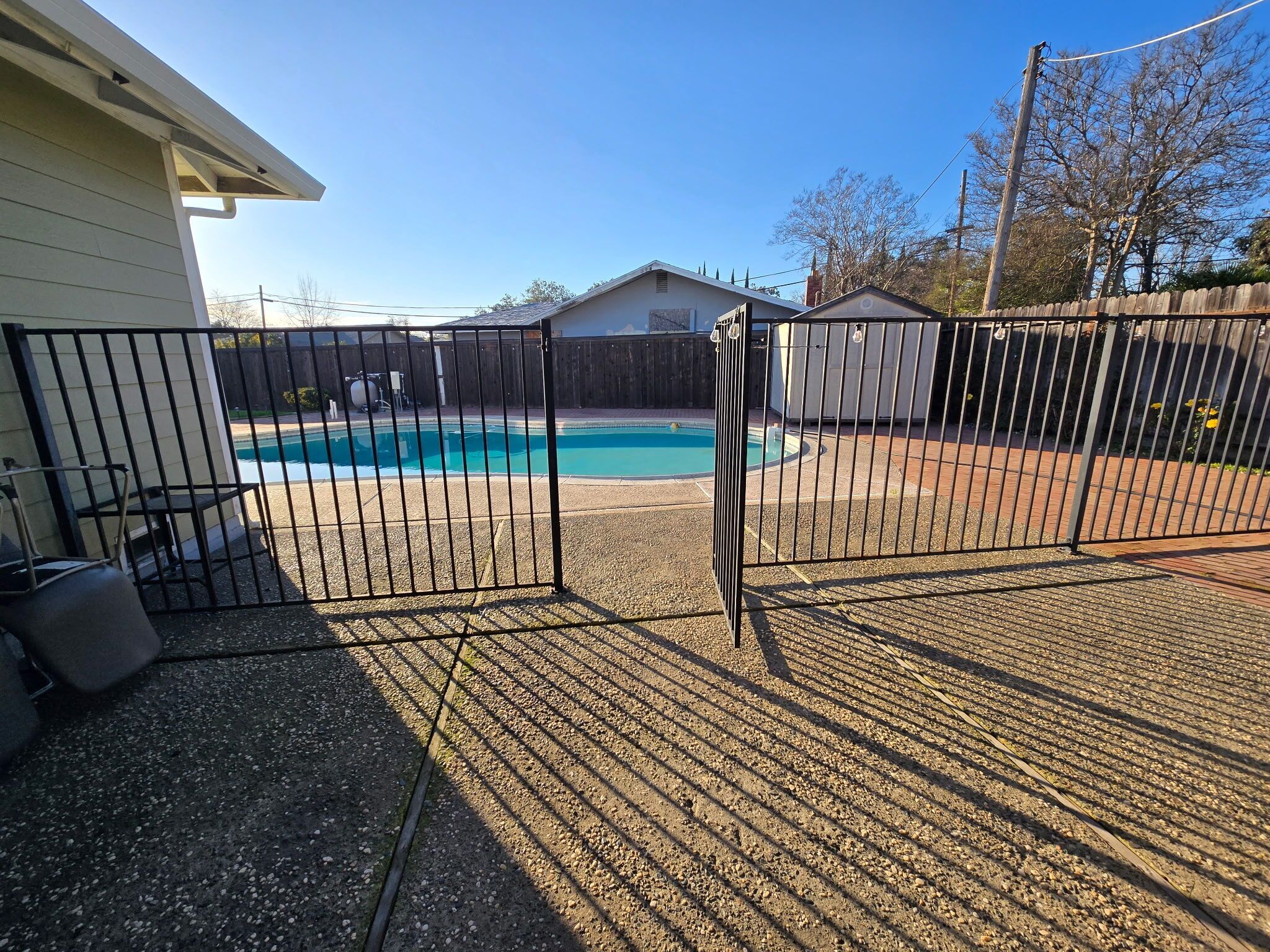 Un jardin avec une piscine, un espace clôturé et une maison.