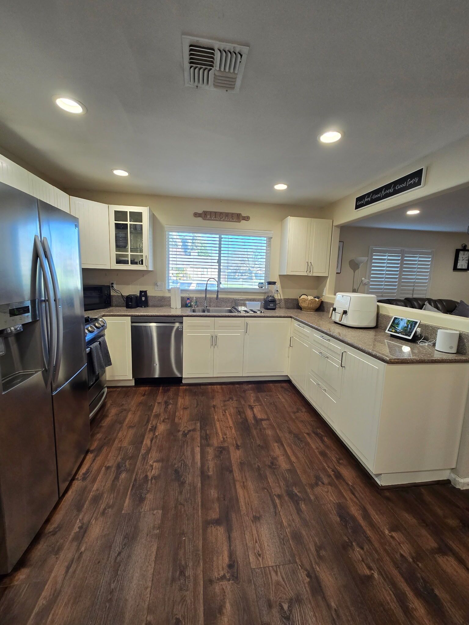 A modern kitchen with stainless steel appliances, white cabinetry, and a wooden floor.