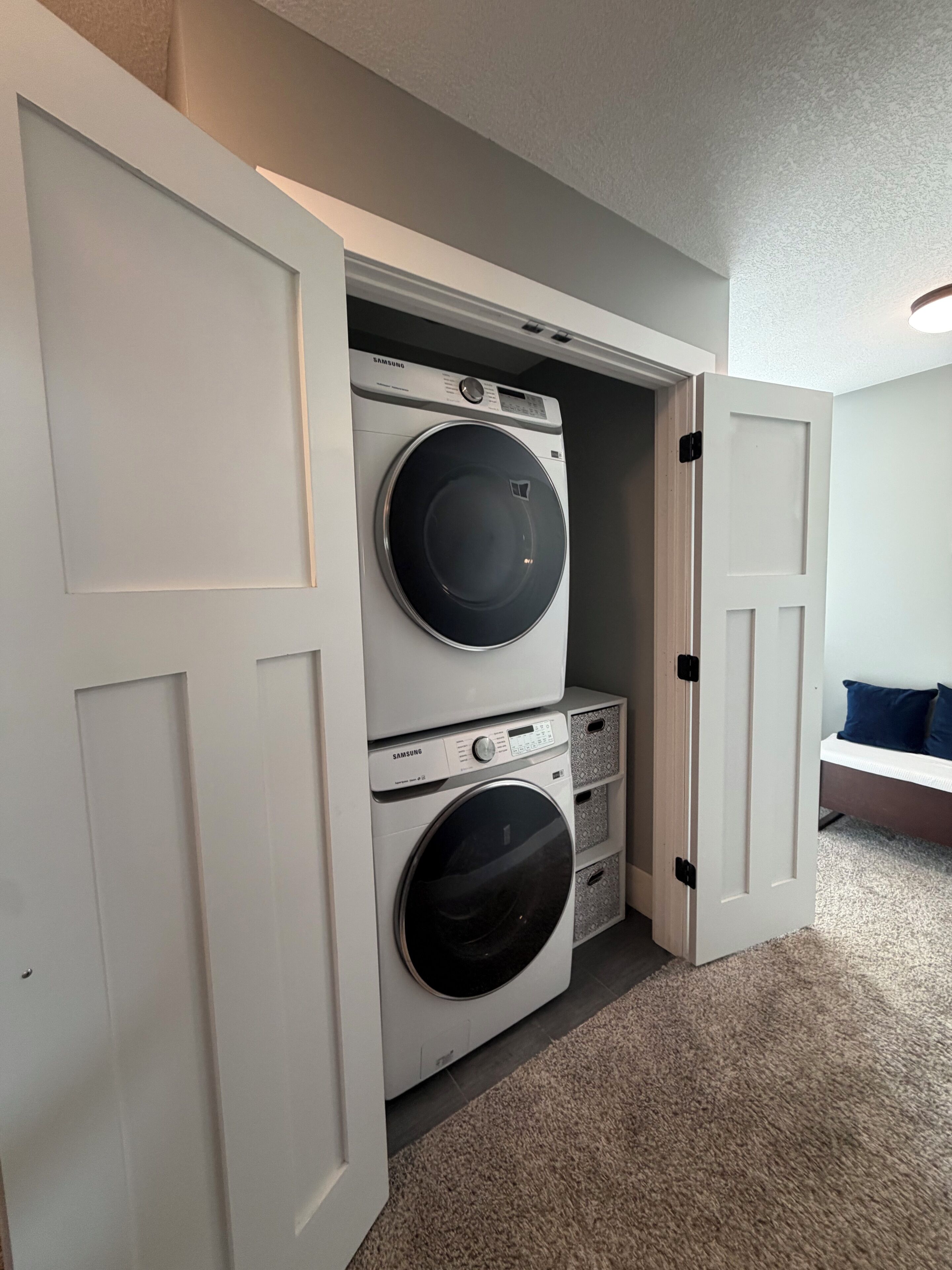 Une buanderie équipée d’un lave-linge et d’un sèche-linge superposés, d’un banc et d’une porte.