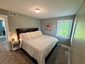 A bedroom with a bed, bedside table, lamp, and a window with blinds. - 3 King Beds Minnehaha Hideaway Near Downtown (Minneapolis)