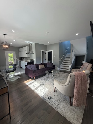A spacious living area with a sofa, coffee table, and a staircase leading to an upper level. - 3 King Beds Minnehaha Hideaway Near Downtown (Minneapolis)