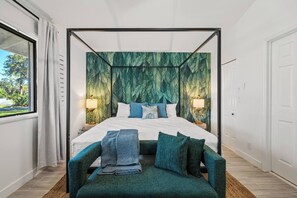 Une chambre à coucher avec un lit à baldaquin, une vue sur la verdure et un banc placé devant le lit.