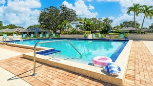 A swimming pool with a blue tiled edge, lounge chairs, and a palm tree in the background. - PGA Resort Home – Heated Pool, Walk to Dining & 15 min Drive to Beaches (Palm Beach Gardens)