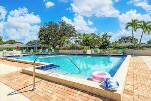 A swimming pool with a blue tiled edge, lounge chairs, and a palm tree in the background. - PGA Resort Home – Heated Pool, Walk to Dining & 15 min Drive to Beaches (Palm Beach Gardens)