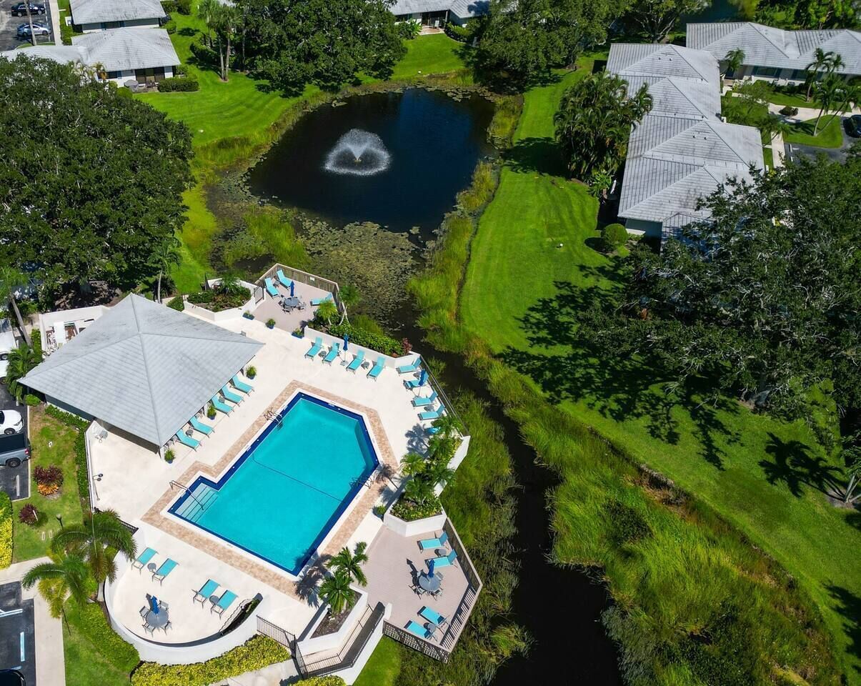 A swimming pool with lounge chairs and a fountain, surrounded by well-maintained lawns and trees.