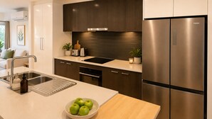 Een moderne keuken met een roestvrijstalen koelkast, een inbouwoven en een spoelbak met een snijplank.