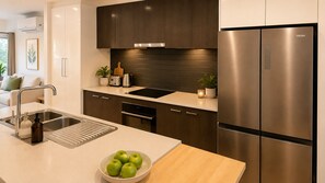 Eine moderne Küche mit einem Edelstahl-Kühlschrank, einem eingebauten Backofen und einer Spüle mit Schneidebrett.
