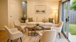 Een woonkamer met een bank, twee fauteuils, een salontafel en een vloerlamp.