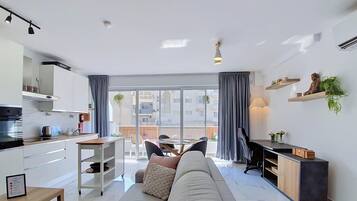 Een moderne woonkamer met een bank, een eettafel en een keukenhoek.