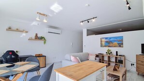 A modern living space with a dining area, a sofa, a coffee table, and a painting on the wall.